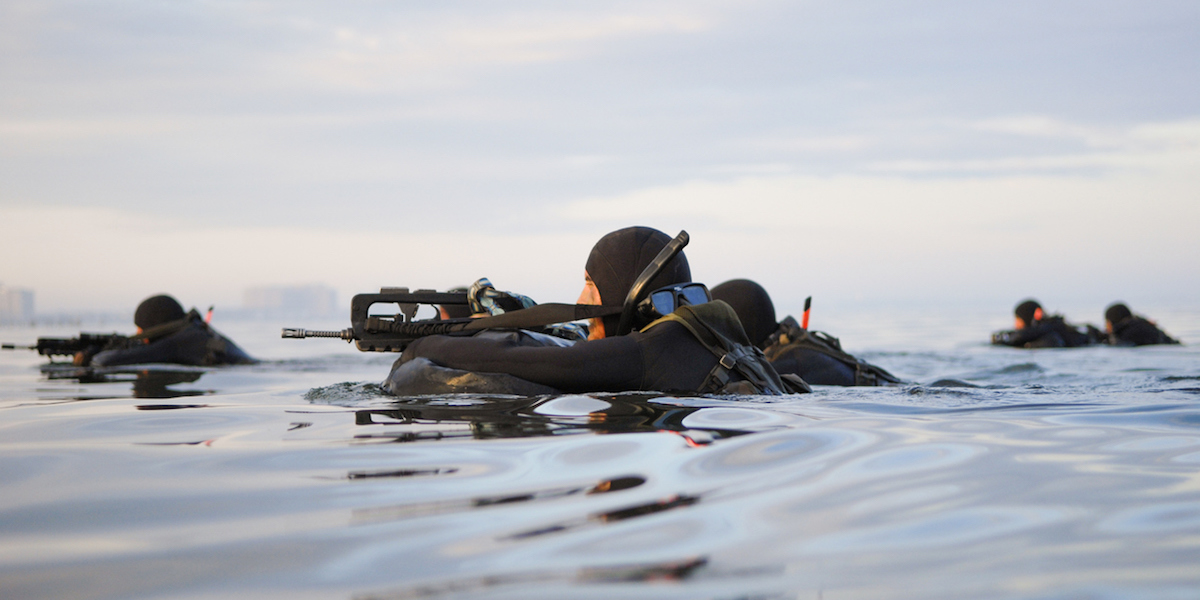Soldiers with guns swim in the sea