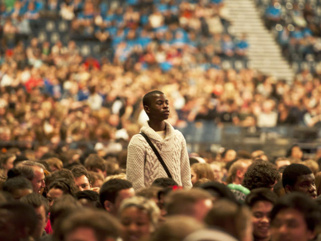 young-man-standing-in-a-seated-crowd_large